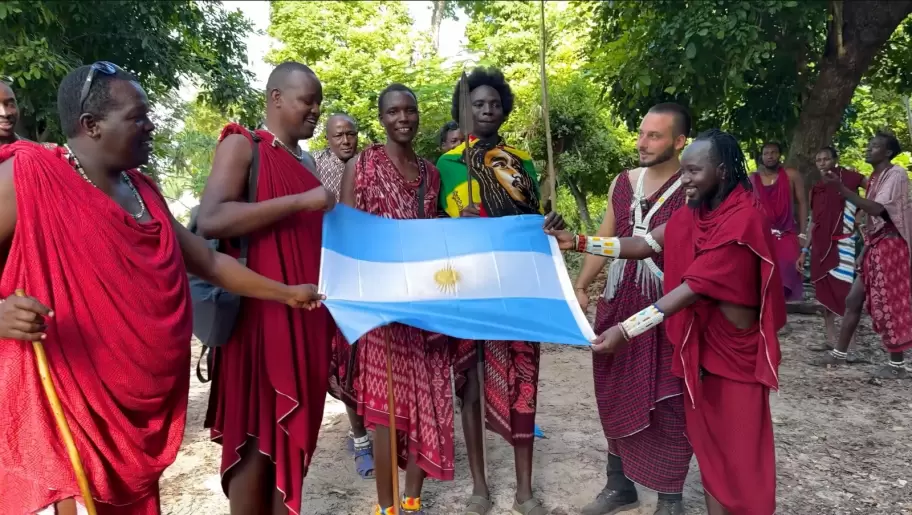 Toms "Tomi" Munaretto con la bandera argentina junto a miembros de la tribu Maasai en Tanzania.