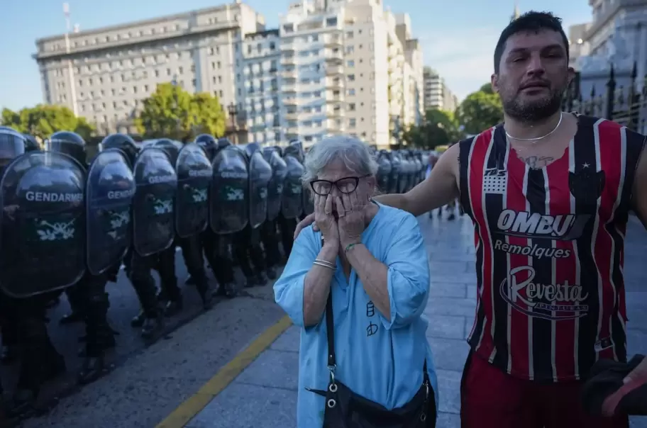 Un hincha ayuda a una jubilada a salir del tumulto represivo